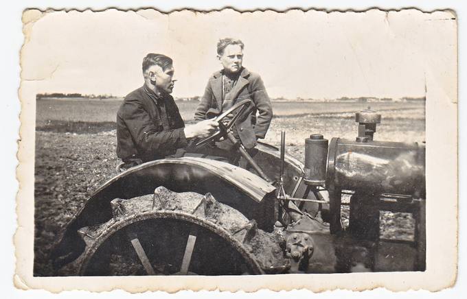 Jonas Zajarskas vairuoja traktorių „Deringa“. Šalia sėdi Steponas Marcinkevičius